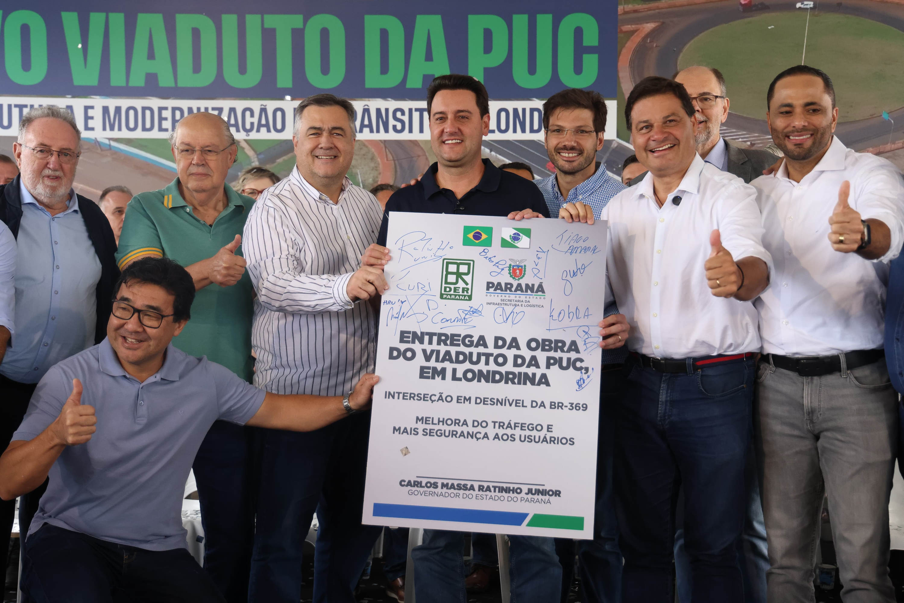 pessoas em frente a placa de inauguração do viaduto puc