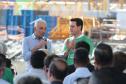 homem falando em cima do palco, ao lado do governador