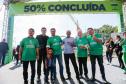 homens em frente a faixa de "50% concluída" da ponte