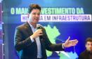 Homem falando no microfone em cima do palco