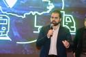 Homem falando no microfone em cima do palco