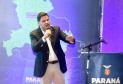 Homem falando no microfone em cima do palco