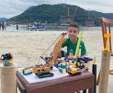 O menino, Felipe Benvinda Guszaki, de 7 anos, usando peças de montar, carrinhos e bonecos de brinquedo para recriar a obra