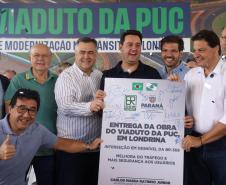 pessoas em frente a placa de inauguração do viaduto puc