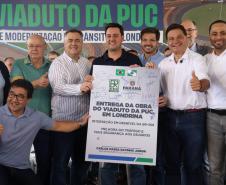 pessoas em frente a placa de inauguração do viaduto puc