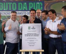 pessoas em frente a placa de inauguração do viaduto puc