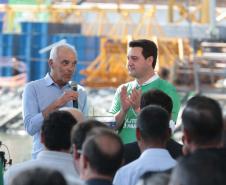 homem falando em cima do palco, ao lado do governador