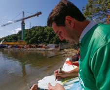 Governador Ratinho Júnior assinando a bandeira com a ponte desenhada