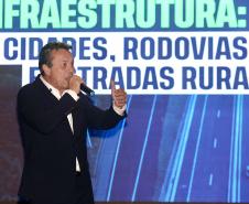Homem falando no microfone em cima do palco