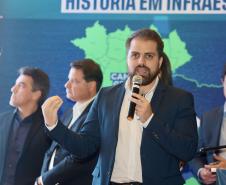 Homem falando no microfone em cima do palco
