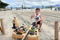 O menino, Felipe Benvinda Guszaki, de 7 anos, usando peças de montar, carrinhos e bonecos de brinquedo para recriar a obra