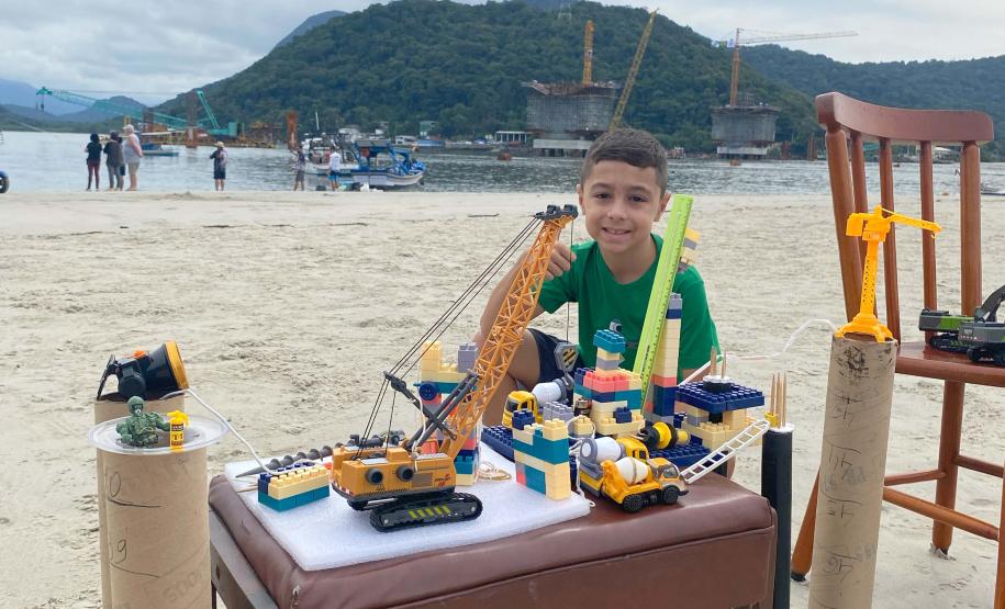 O menino, Felipe Benvinda Guszaki, de 7 anos, usando peças de montar, carrinhos e bonecos de brinquedo para recriar a obra