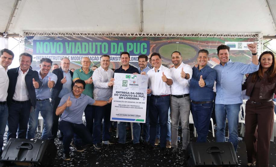 pessoas em frente a placa de inauguração do viaduto puc