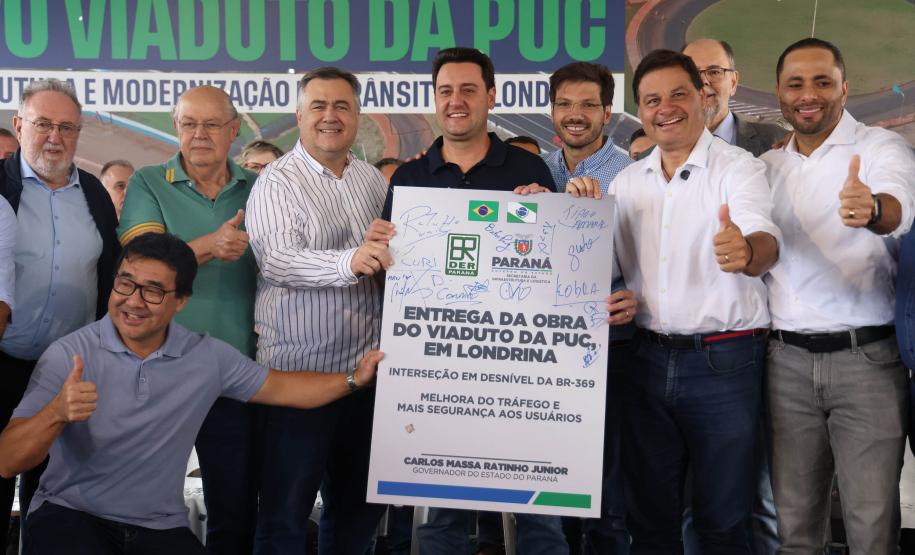 pessoas em frente a placa de inauguração do viaduto puc