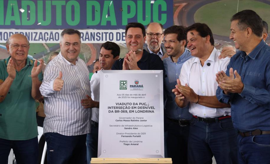 pessoas em frente a placa de inauguração do viaduto puc