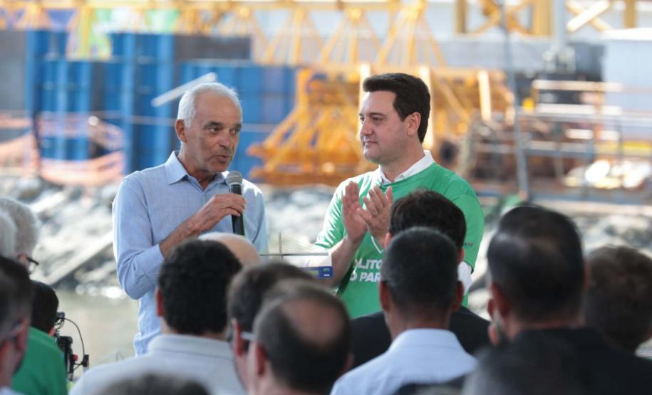 homem falando em cima do palco, ao lado do governador