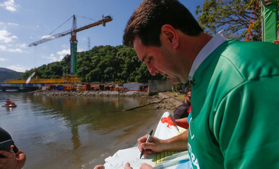 Governador Ratinho Júnior assinando a bandeira com a ponte desenhada