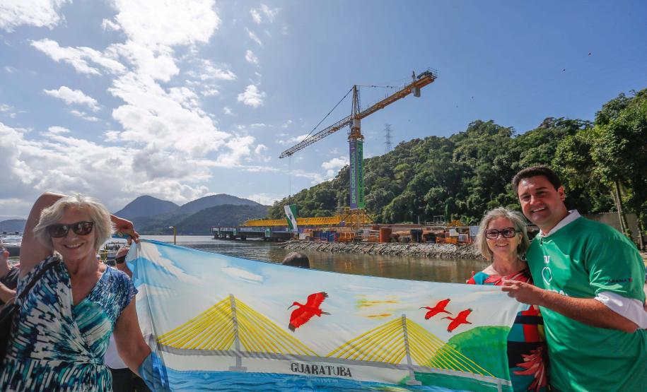 Governador Ratinho Júnior e duas mulheres segurando uma bandeira com a ponte desenhada
