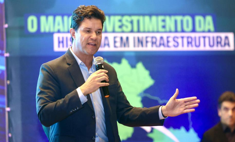 Homem falando no microfone em cima do palco