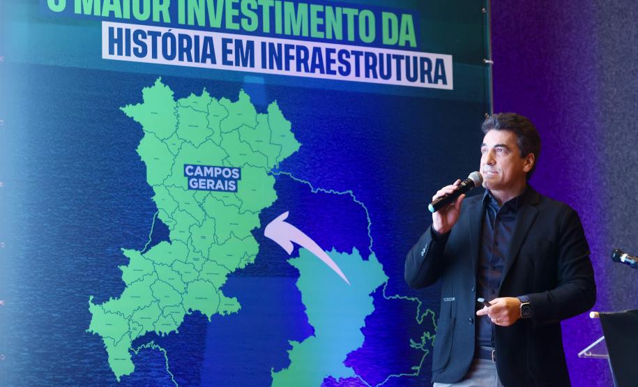 Homem falando no microfone em cima do palco