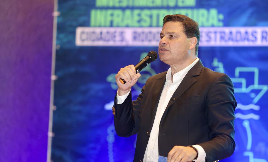 Homem falando no microfone em cima do palco